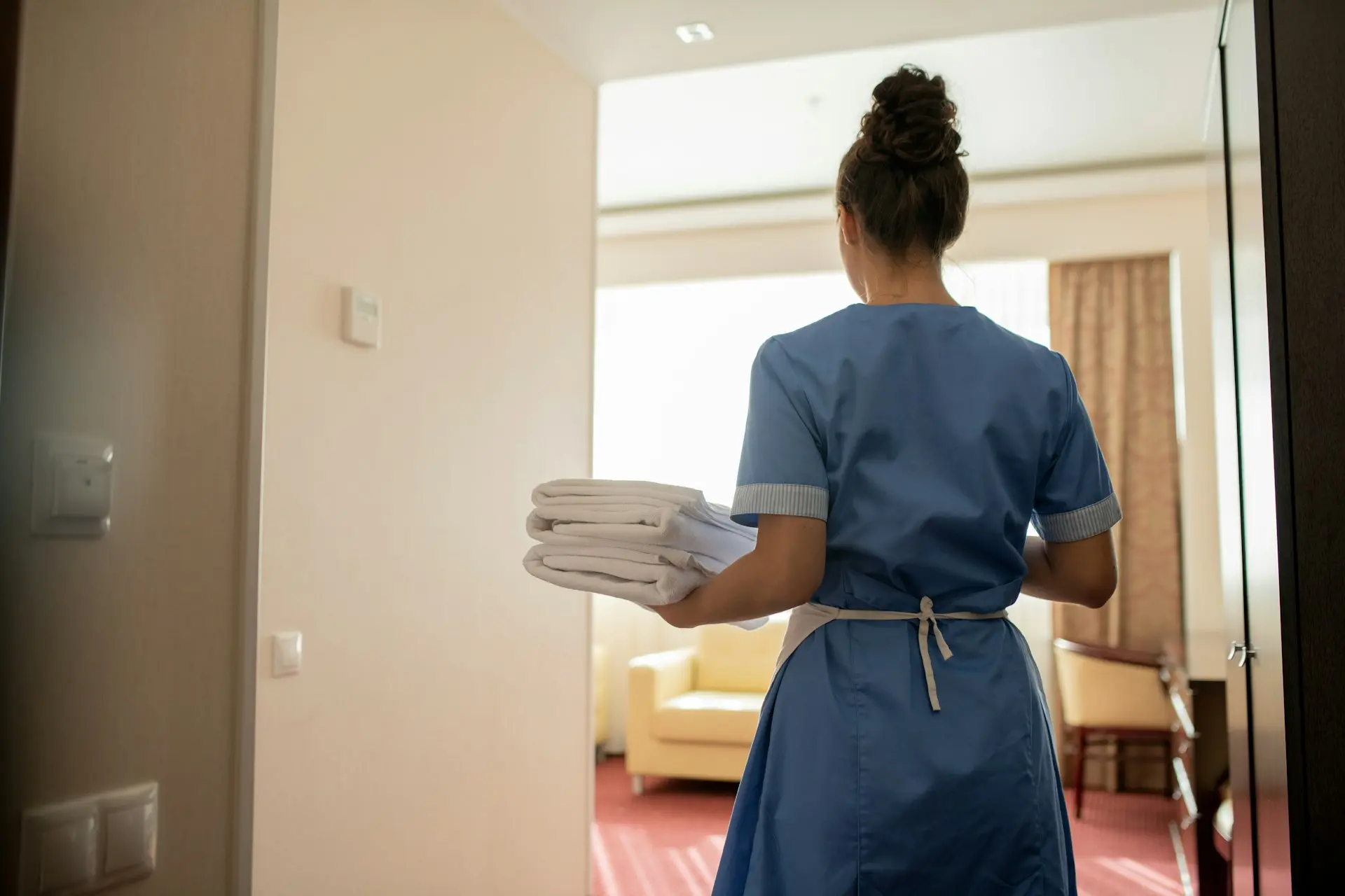 Eine Mitarbeiterin des Reinigungsdienstes wechselt die Handtücher in einem Hotelzimmer