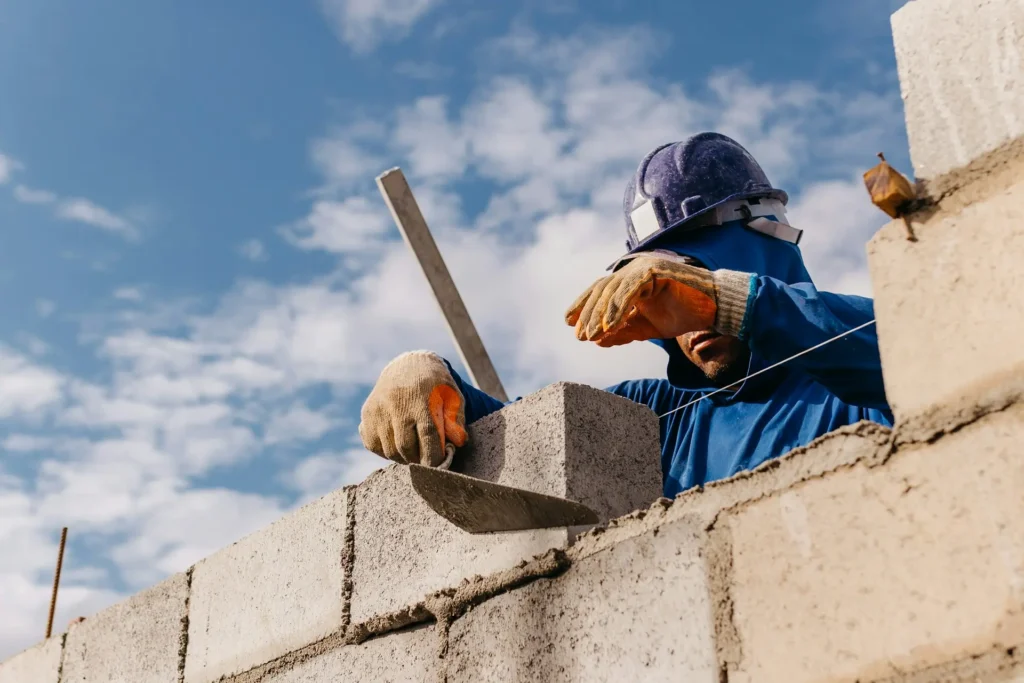 Maurer setzt einen Stein auf eine Mauer auf der Baustelle